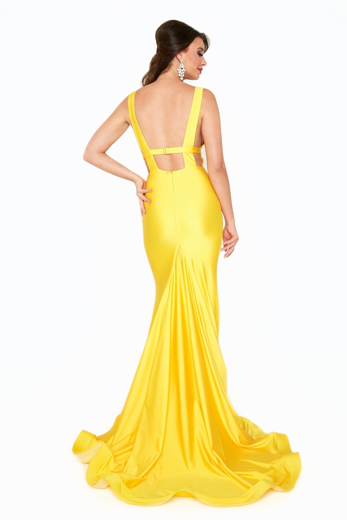 Woman wearing the Atria 6539H Waistband Deep V-Neck Long Prom Dress with a mermaid silhouette, standing against a white background and glancing over her shoulder.